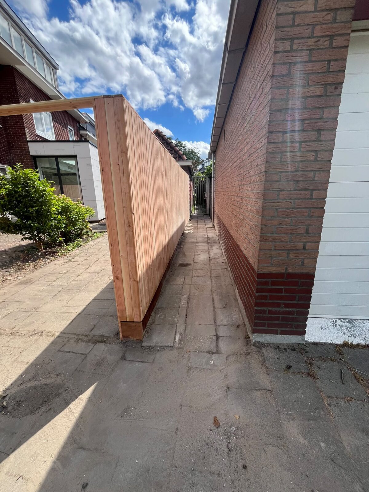 Houten schutting in een smalle doorgang naast een woning